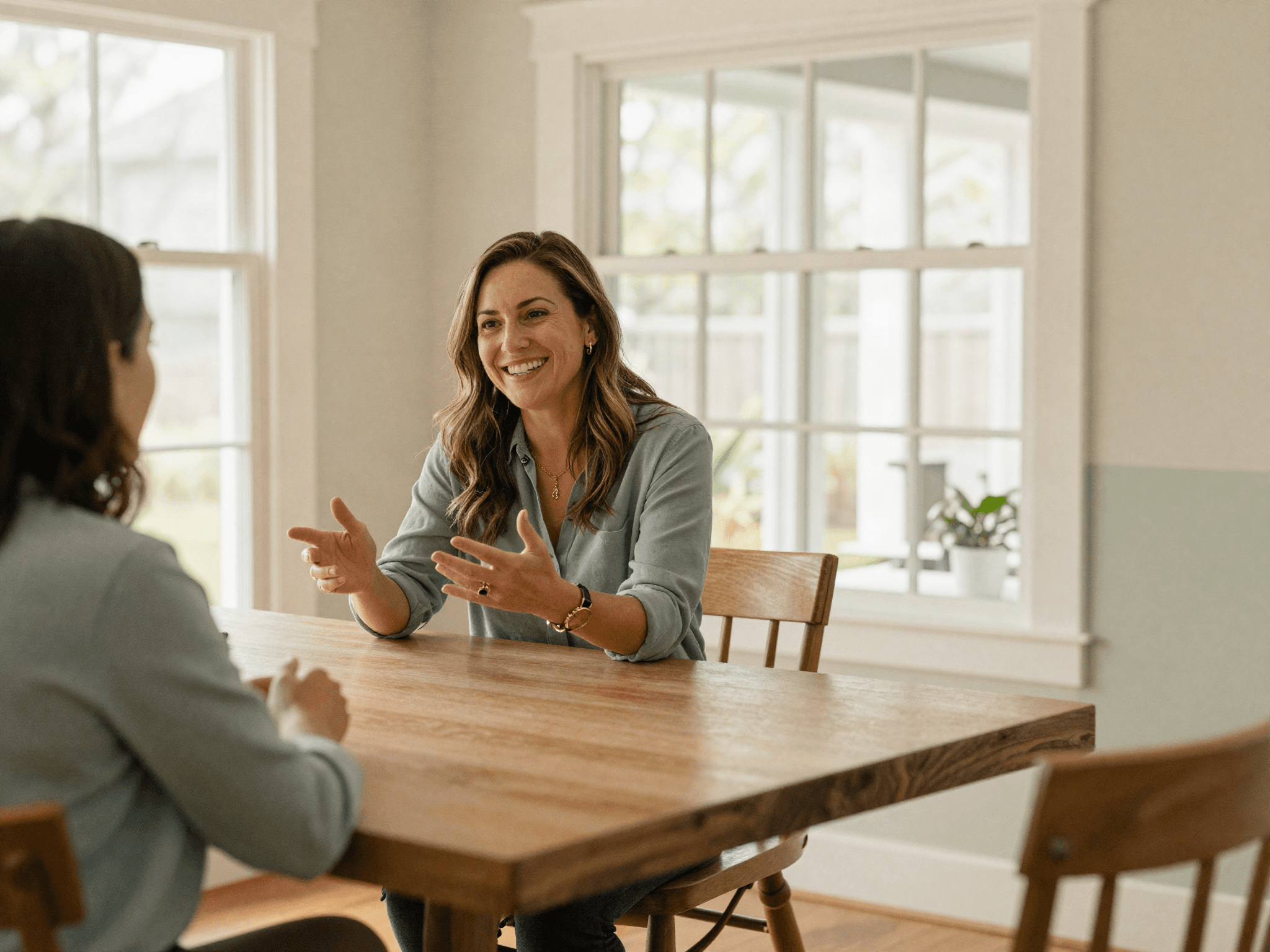 Lynda talking with a client across a table, mid-conversation